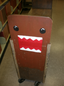 ④UCLAの大学図書館で出会った、あのキャラクター (2007年中川正紀撮影) ブックトラックの側面に日本の某放送局の着ぐるみキャラクター の姿が・・・!もうすでに日本文化の輸出品の一つになっている んでしょうか。いや~、驚きました。思わずシャッターを切って しまいました。あの日本語の決め台詞が現地でも通じるんでしょ うか。今度、試してみようかと思います。